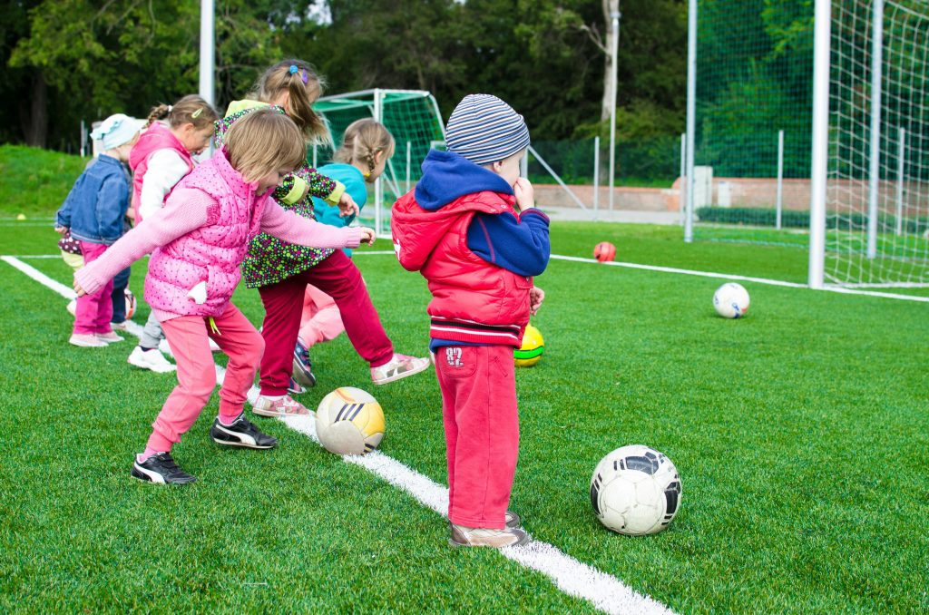 pexels-photo-296302-296302 Kids having fun playing soccer outdoors on a sunny day in a park.