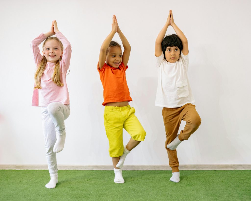 pexels-photo-8613312-8613312 Three diverse children practicing yoga indoors, showcasing joy and balance.